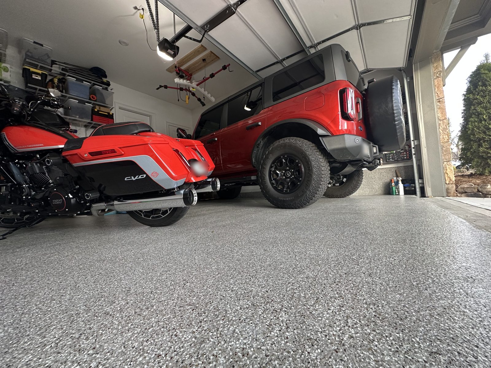 Finished two-car garage floor with a red Bronco and motorcycle parked on gray flake