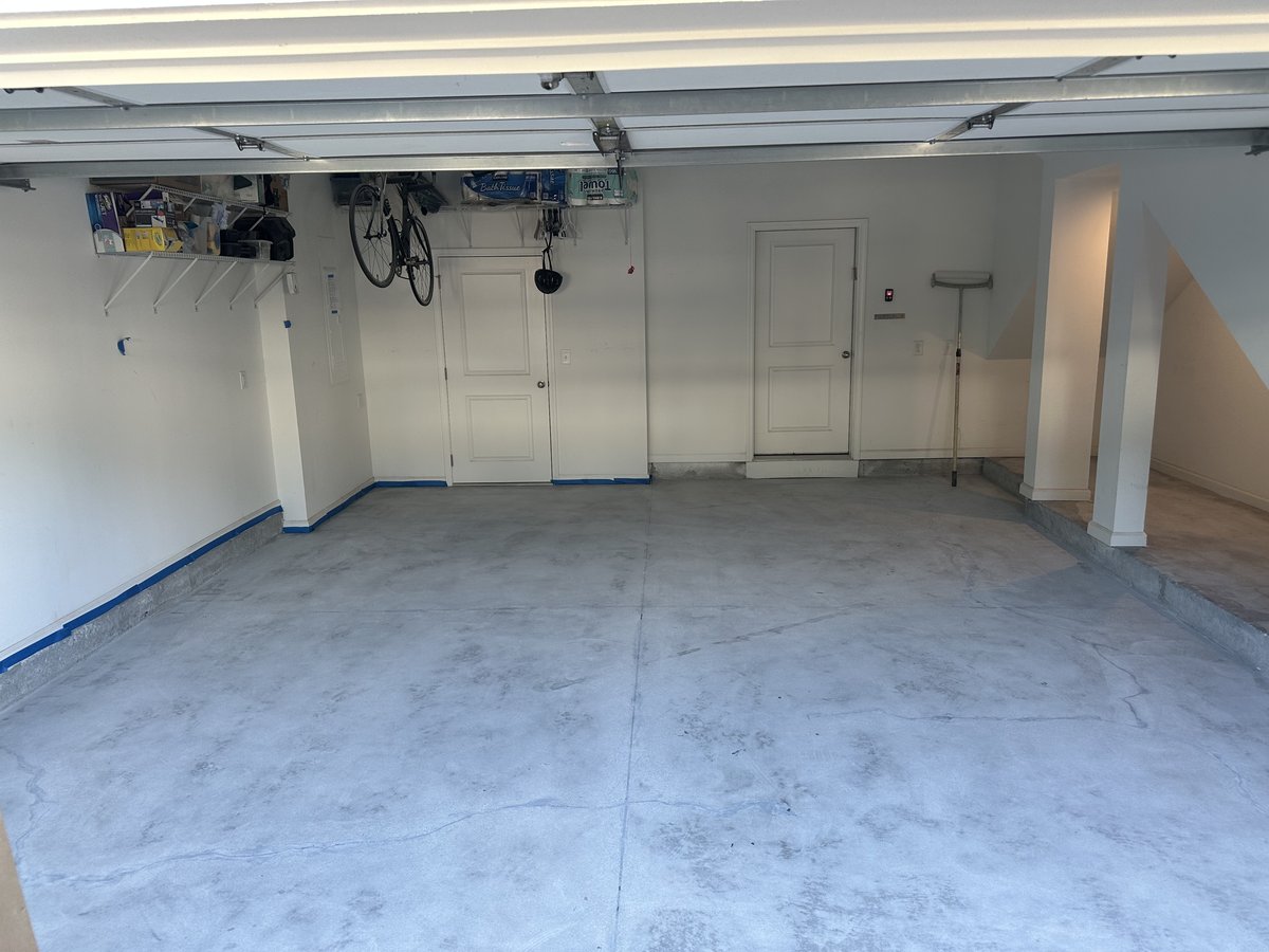 Garage floor before coating - bare concrete with blue tape prep
